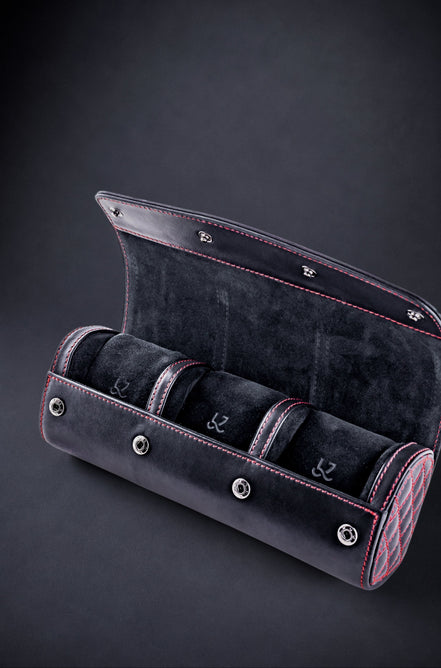 Black velvet watch case with three compartments on a dark background