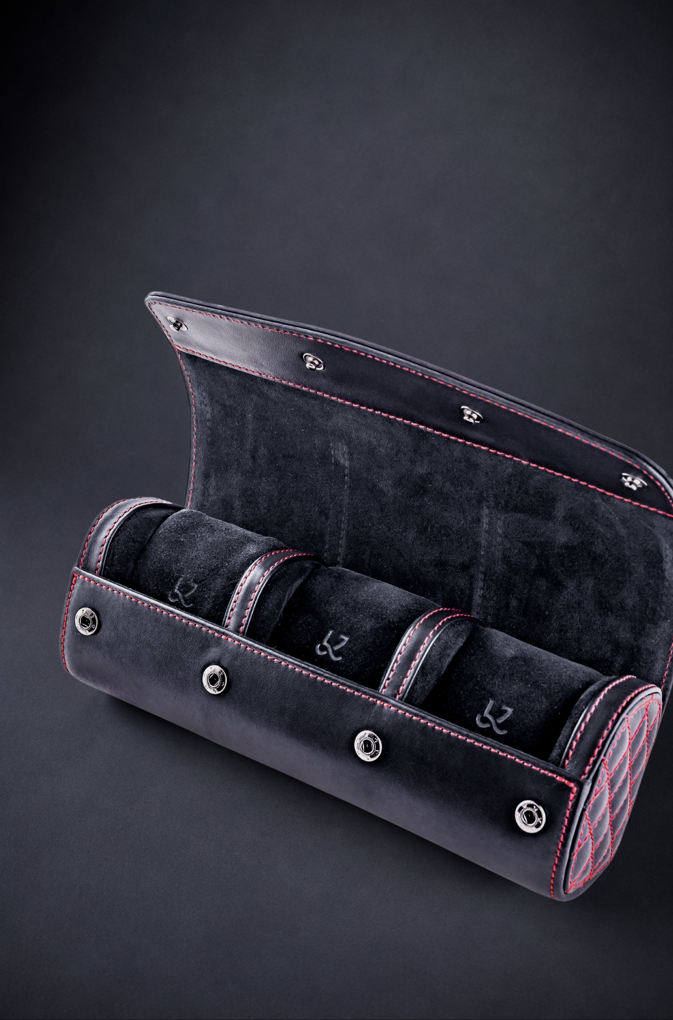 Black velvet watch case with three compartments on a dark background