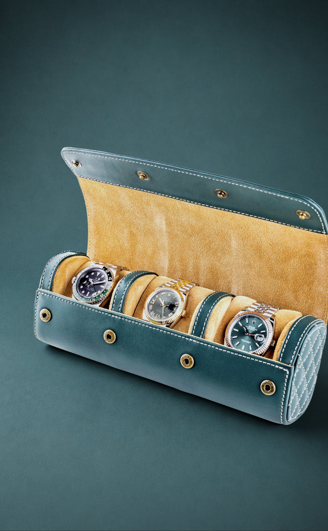British racing green watch roll with mustard interior containing three watches on a dark green background