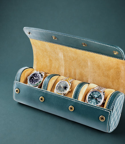 British racing green watch roll with mustard interior containing three watches on a dark green background
