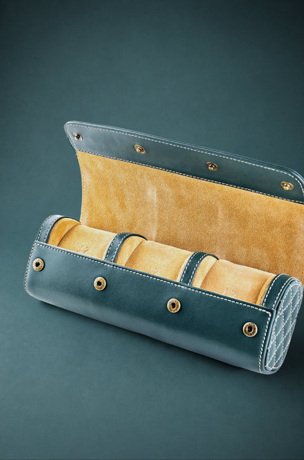 British racing green watch roll with mustard interior containing three watches on a dark green background