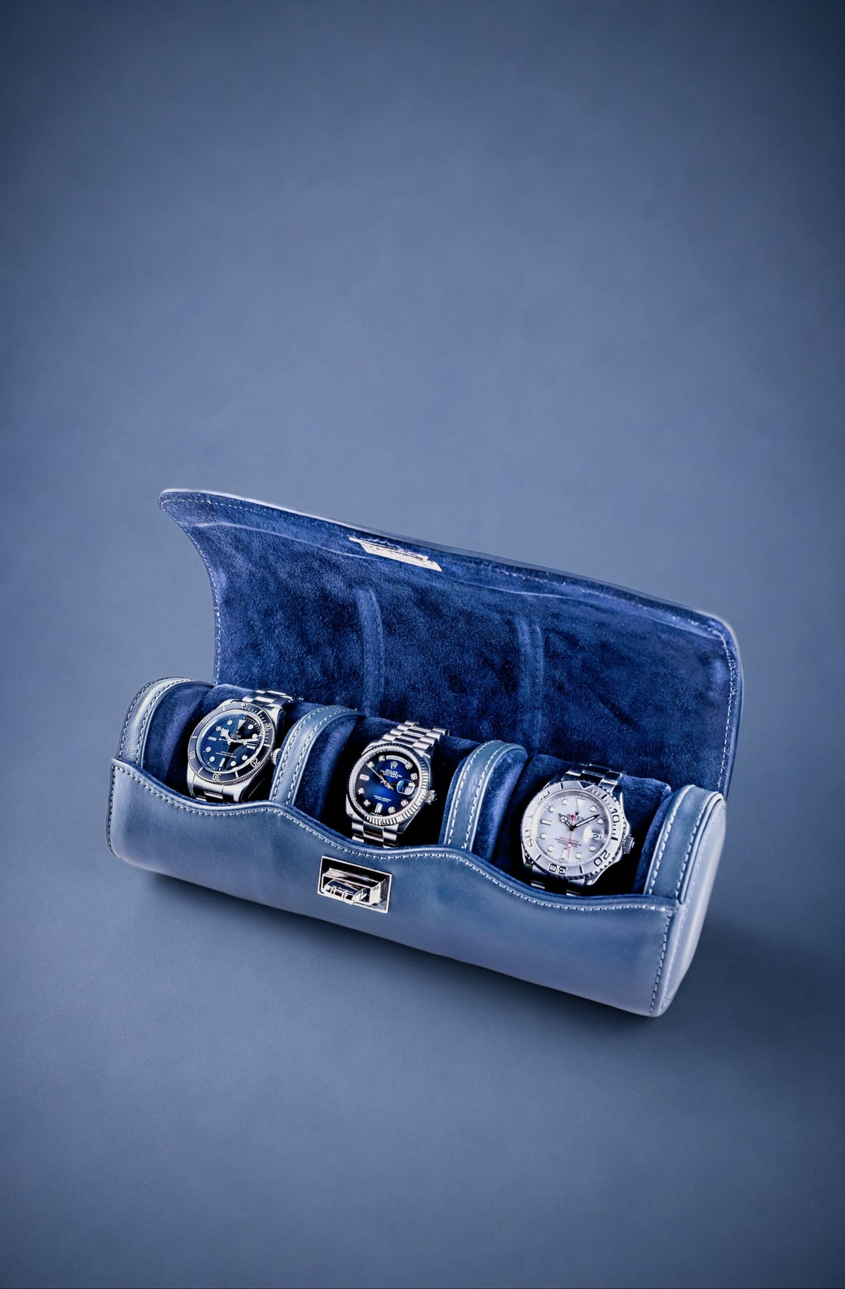 Navy Blue velvet watch roll with three watches on a blue background