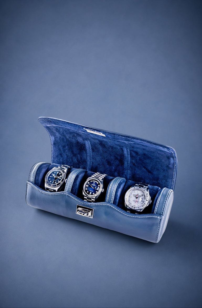 Navy Blue velvet watch roll with three watches on a blue background