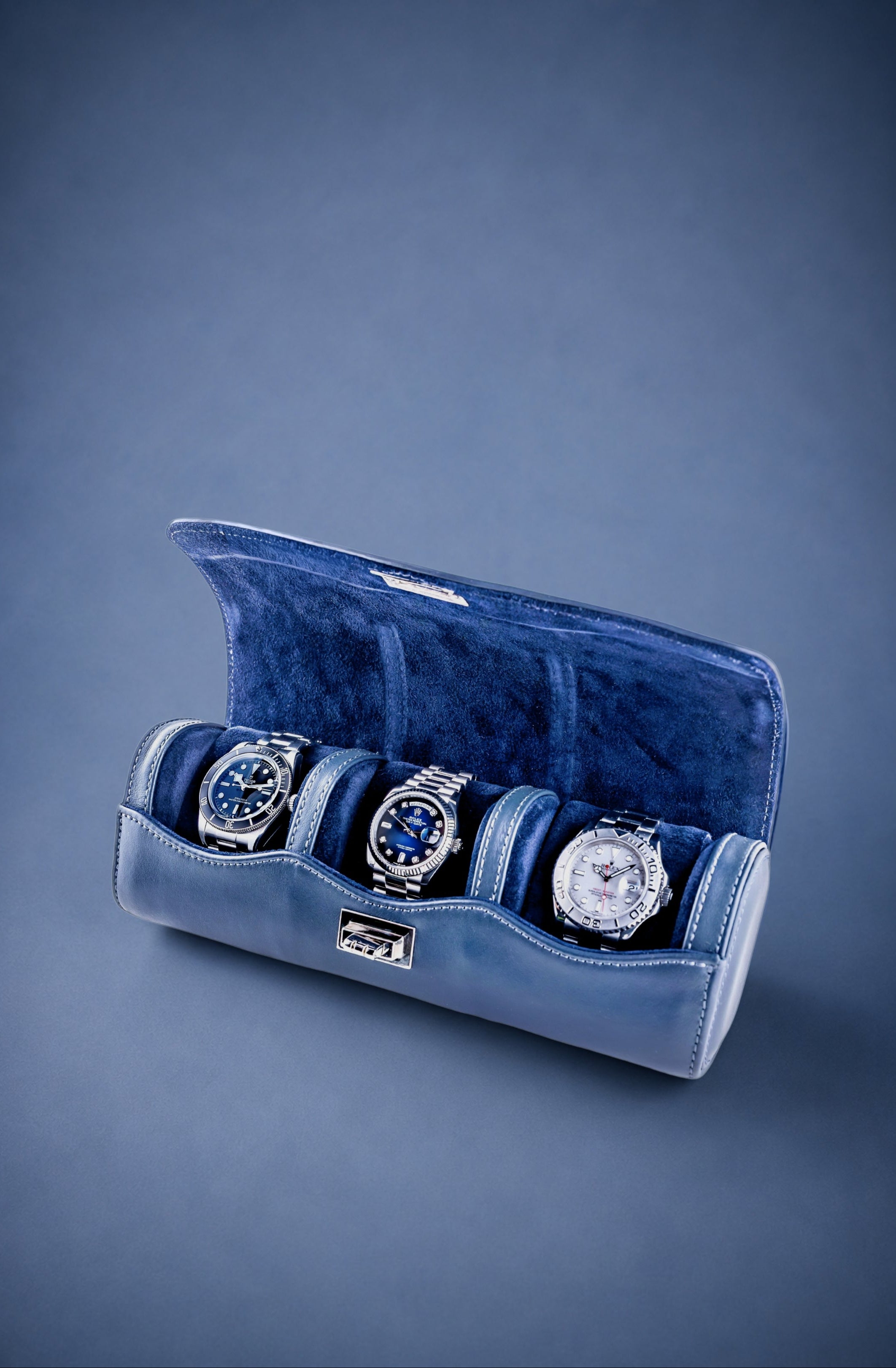 Navy Blue velvet watch roll with three watches on a blue background