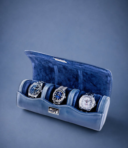 Navy Blue velvet watch roll with three watches on a blue background