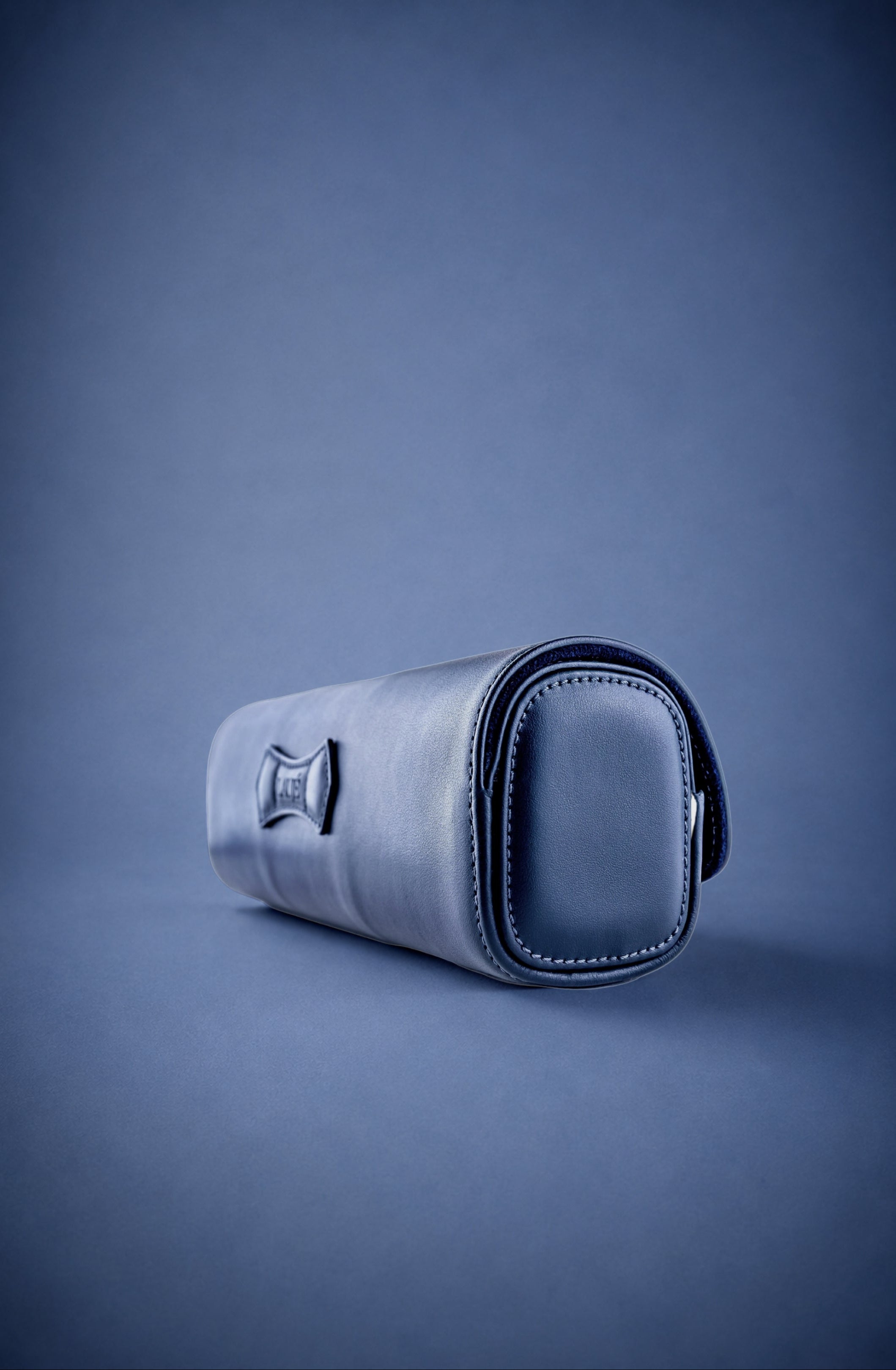 Navy Blue leather watch roll with three watches on a blue background