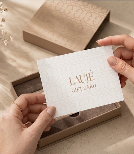 Person holding a white Laujé gift card with  in a decorative setting.