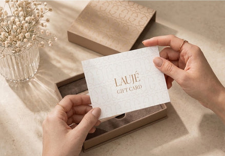 Person holding a white Laujé gift card with  in a decorative setting.